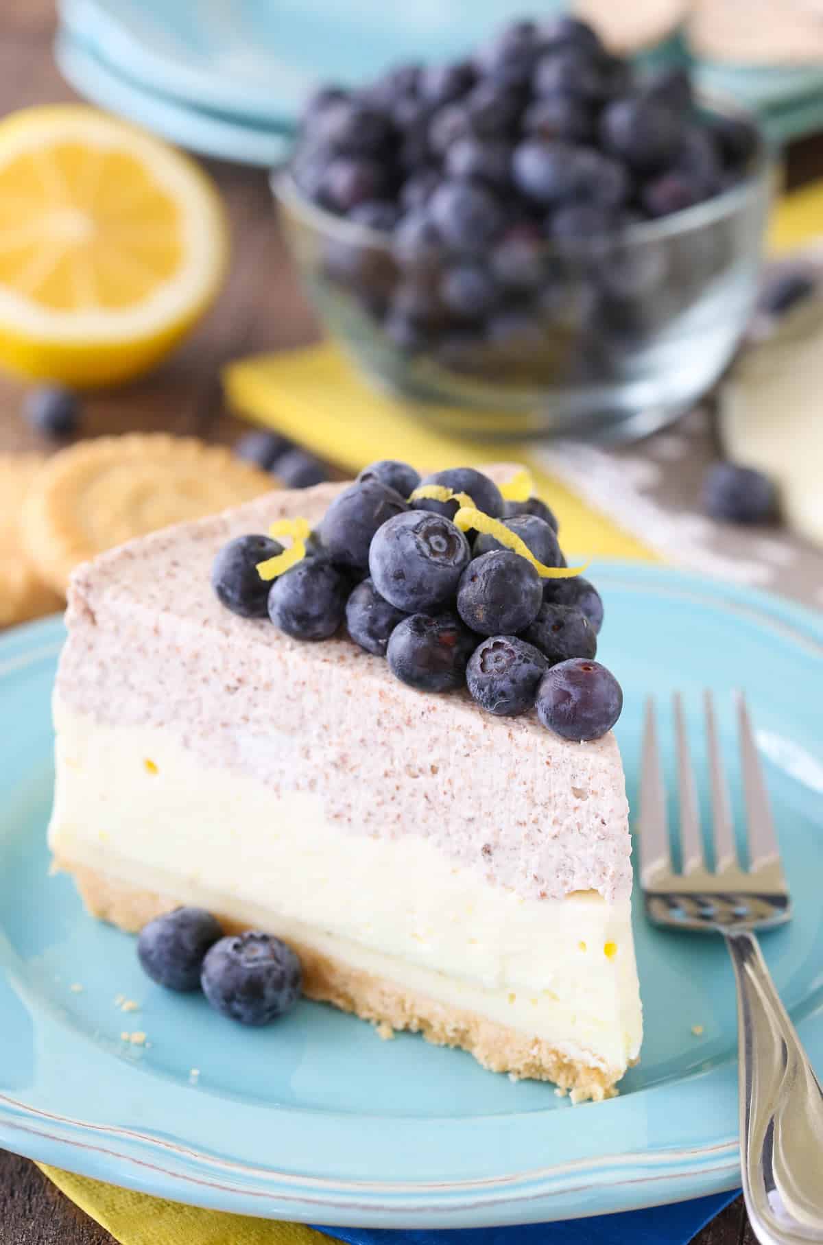 Side view of a slice of lemon blueberry shortbread mousse cake on a small blue plate.