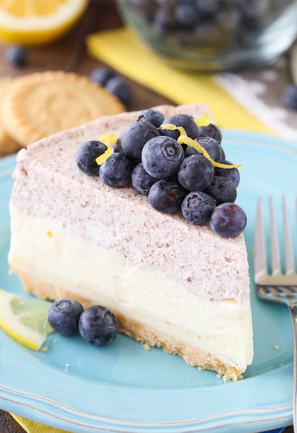 Close up of a slice of lemon blueberry shortbread mousse cake on a small blue plate.