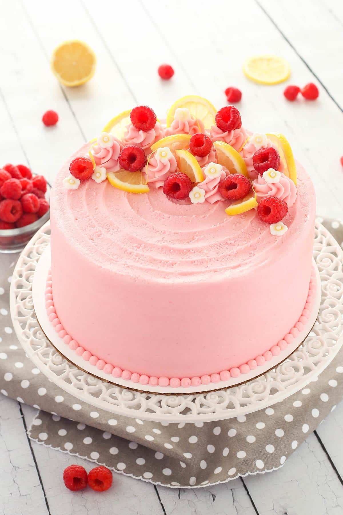 Close up of a lemon raspberry cake on a white cake stand.
