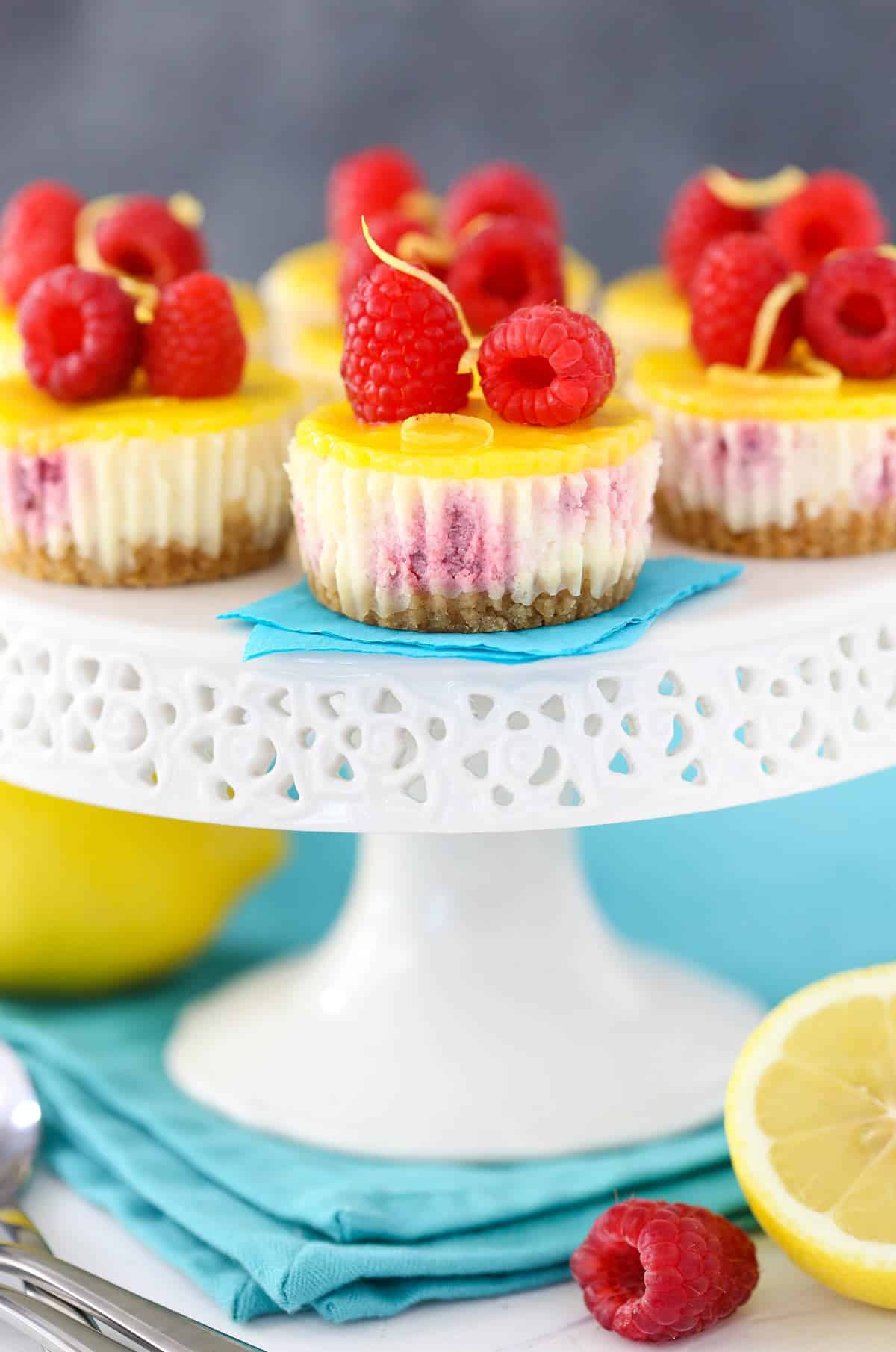 Mini lemon raspberry cheesecakes on a white cake stand.