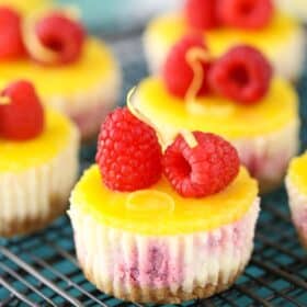 Close up of mini lemon raspberry cheesecakes on a wire rack.