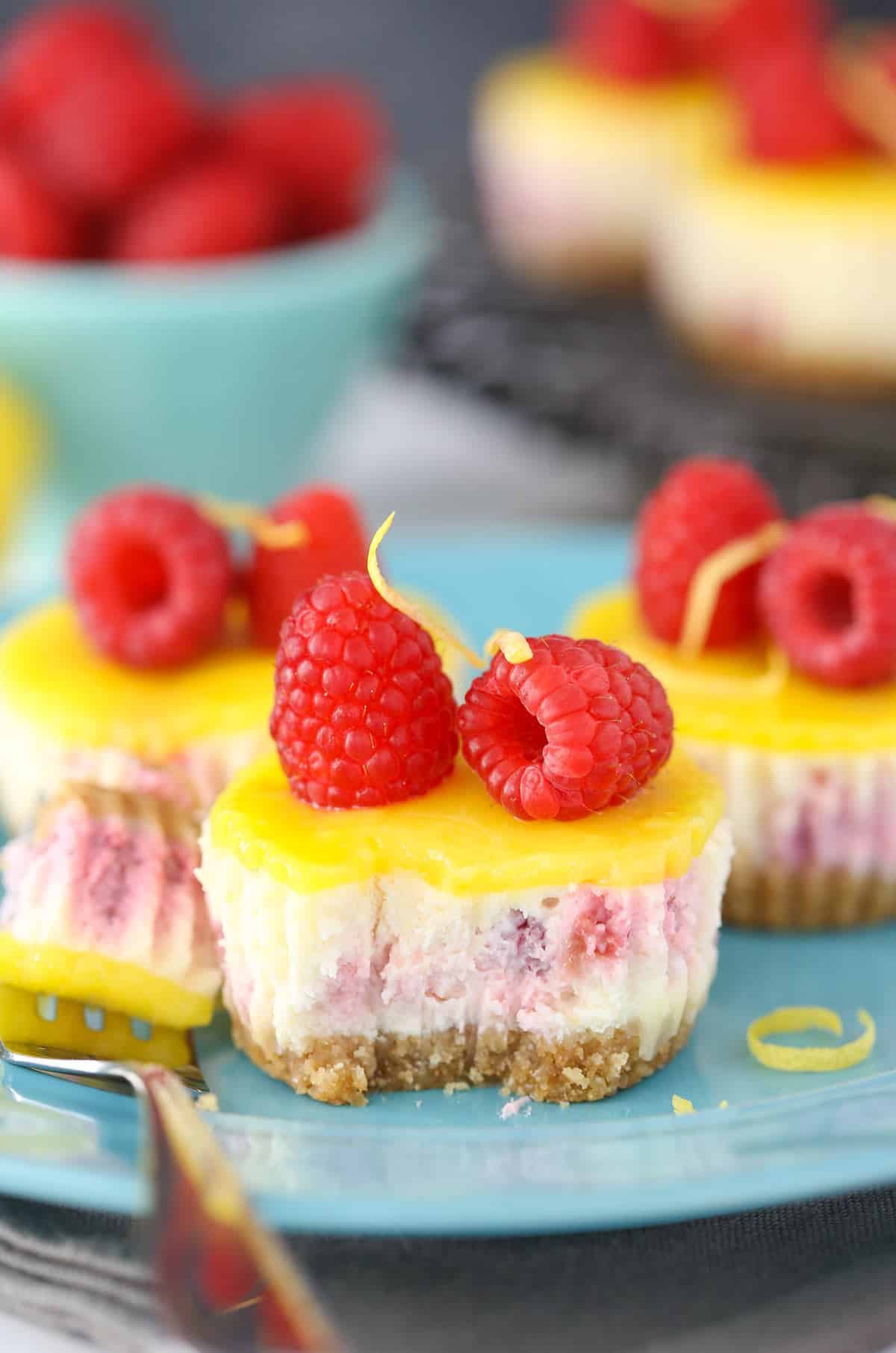 Close up of a mini lemon raspberry cheesecake with a bite removed on a fork.