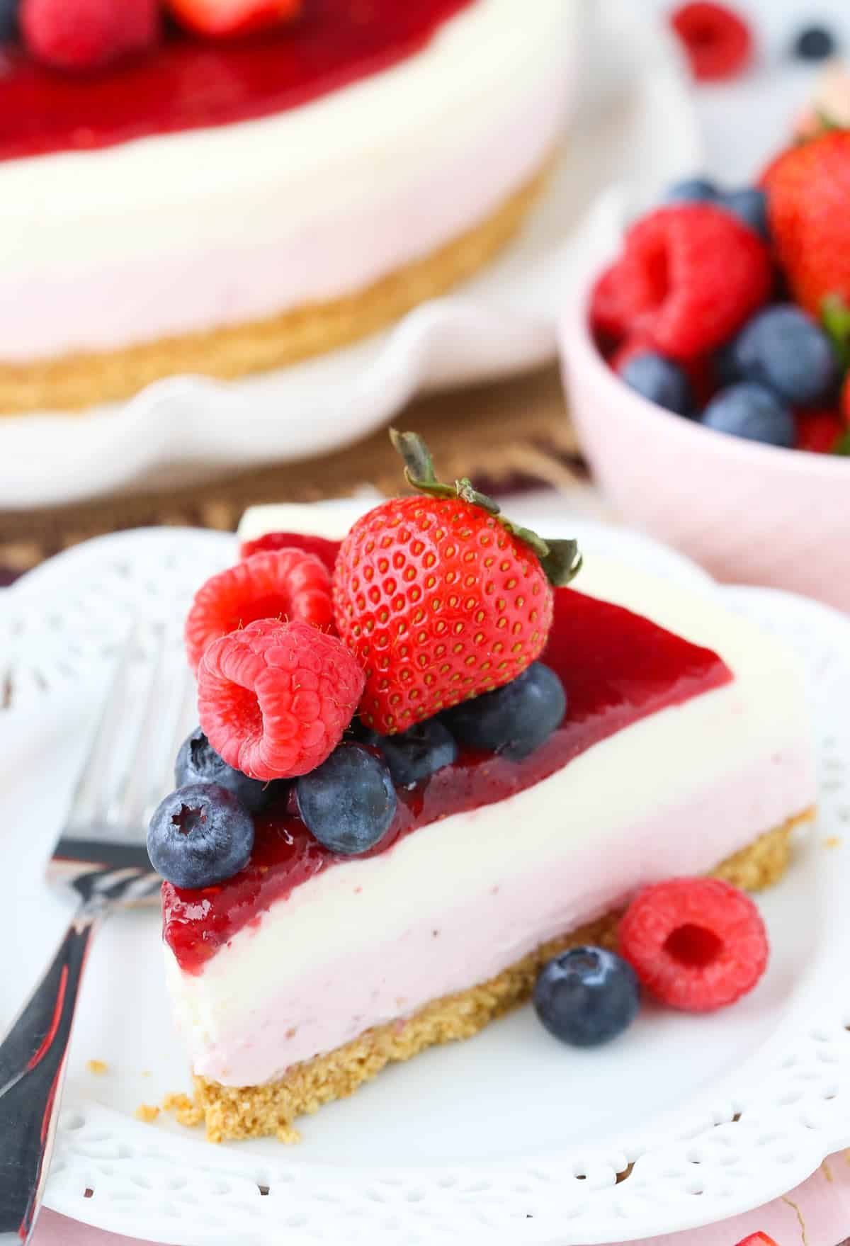 Close up of a slice of no bake berry vanilla cheesecake on a small white plate.