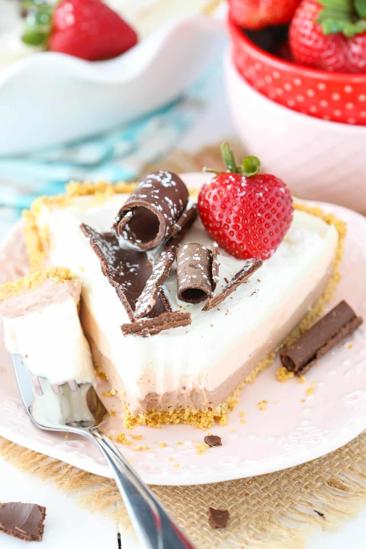 A slice of no bake neapolitan cheesecake pie with a bite removed on a fork.