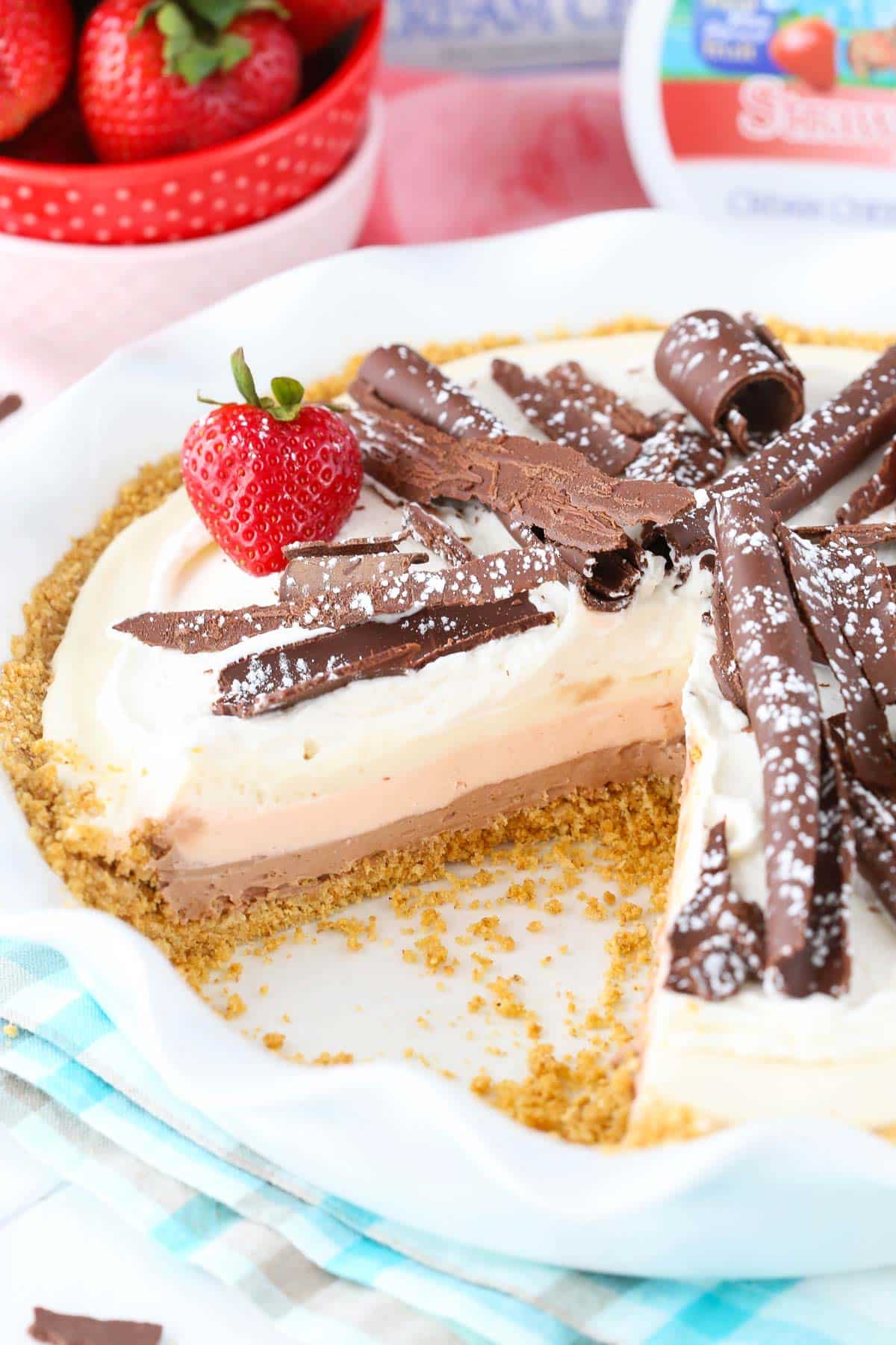 A no bake neapolitan cheesecake pie with a slice removed to show layers.