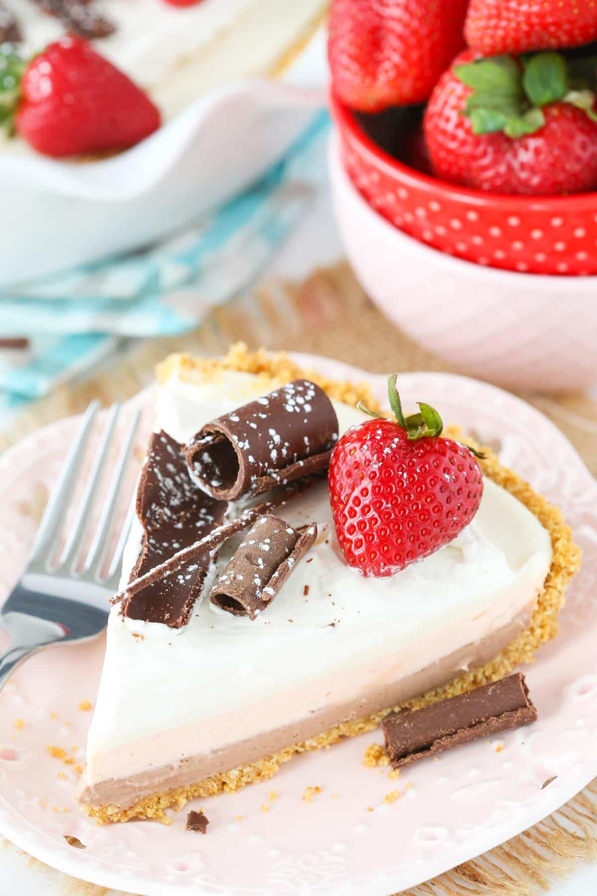 A slice of no bake neapolitan cheesecake pie on a white plate.