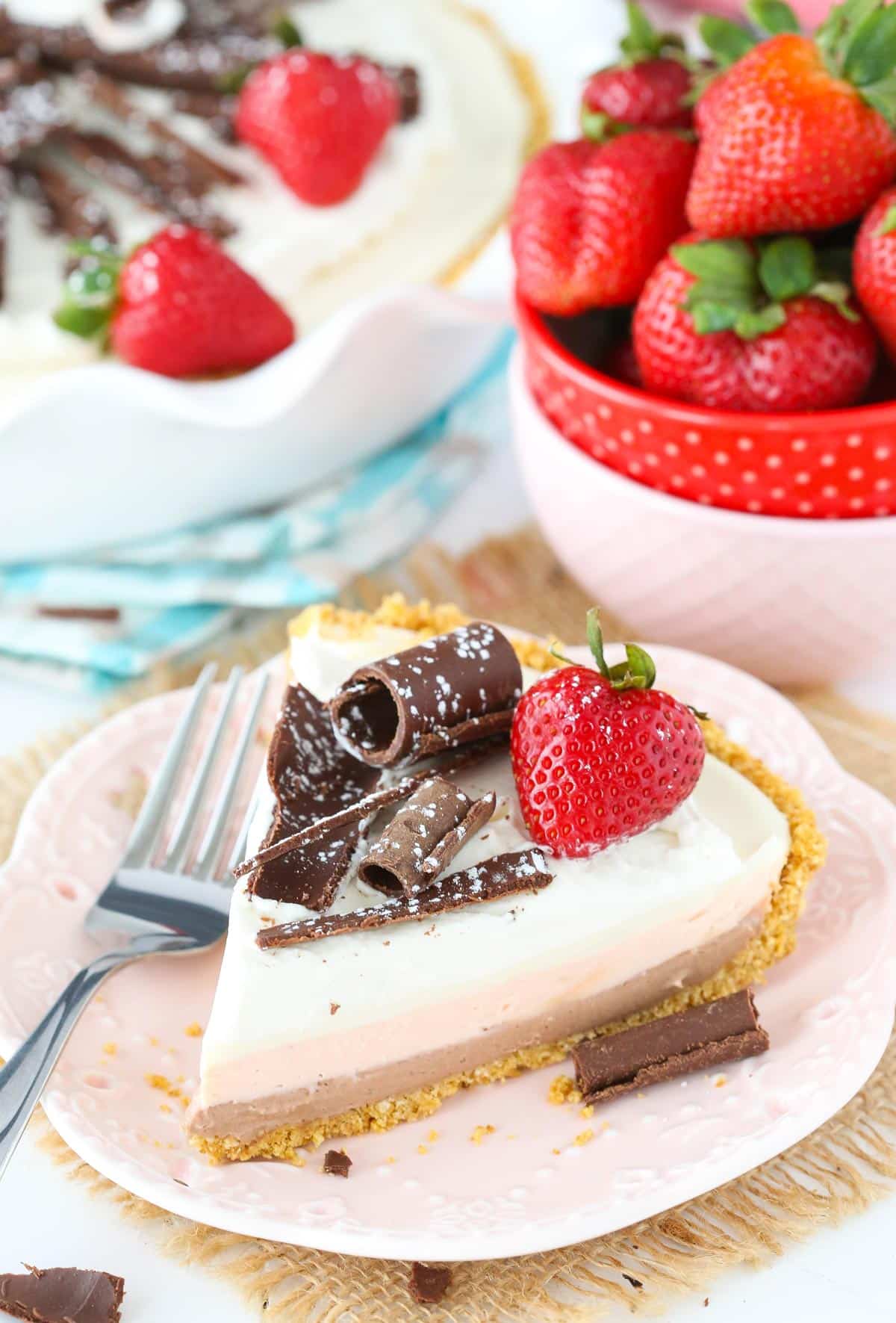A slice of no bake neapolitan cheesecake pie on a small white plate.