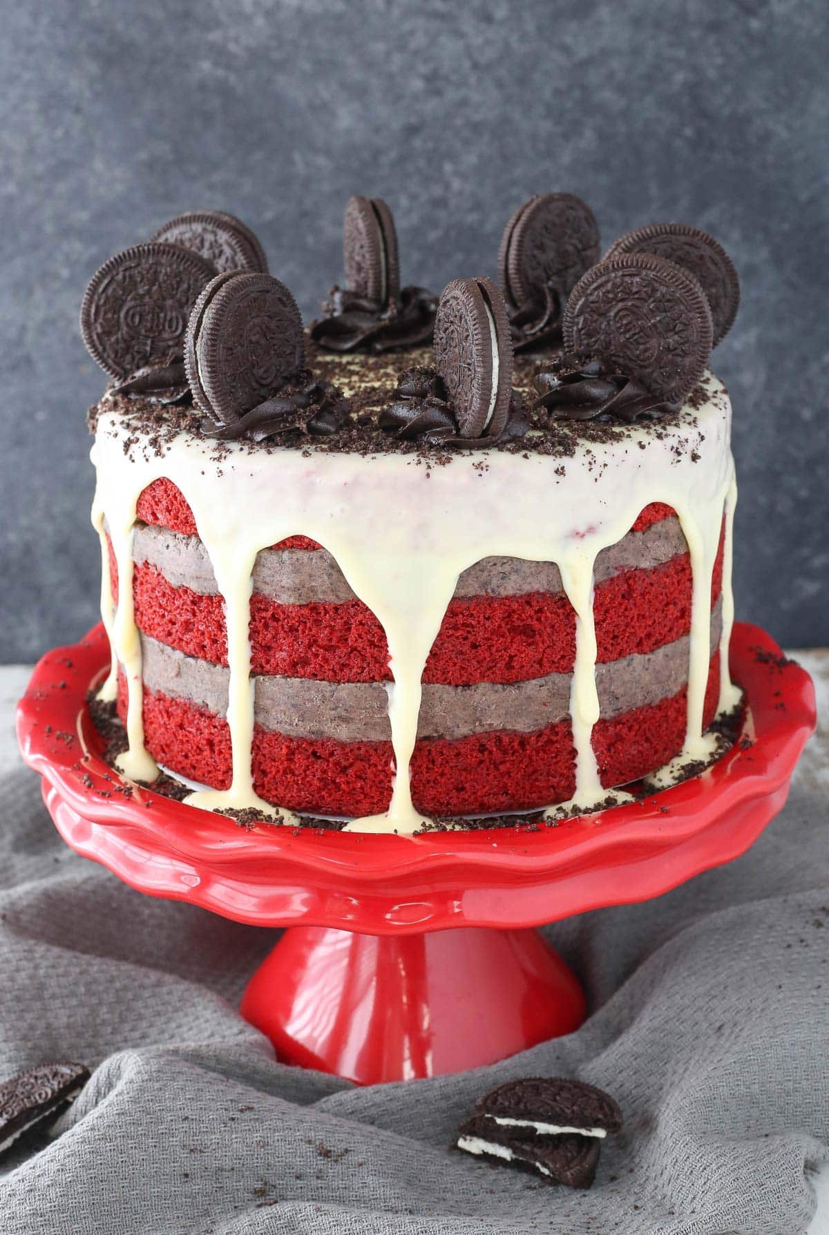 An Oreo cookie dough red velvet blondie layer cake on a red cake plate.