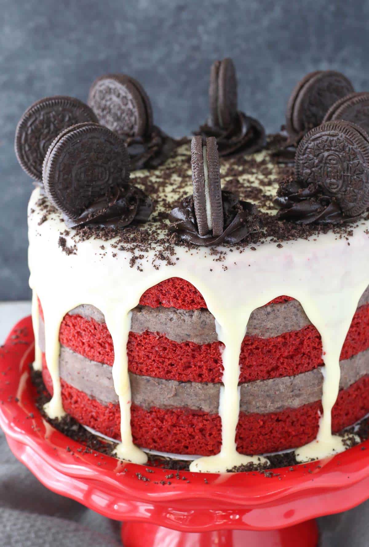 Close up of the side of an Oreo cookie dough red velvet blondie layer cake on a red cake plate.