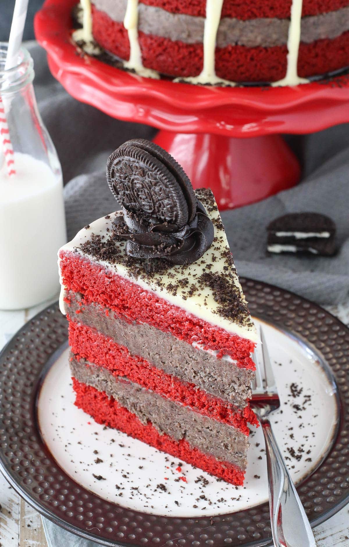 Overhead view of a slice of Oreo cookie dough red velvet blondie layer cake on a black and white plate.