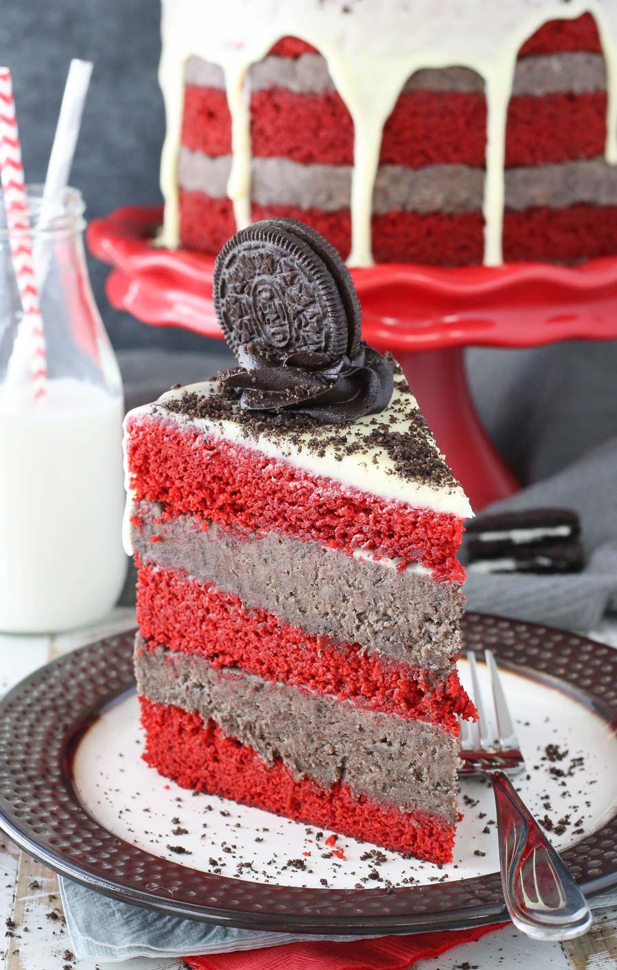 A slice of Oreo cookie dough red velvet blondie layer cake on a black and white plate.