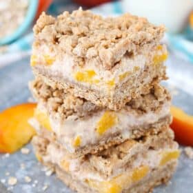 Three peach cinnamon oatmeal cheesecake bars stacked one on top of the other.