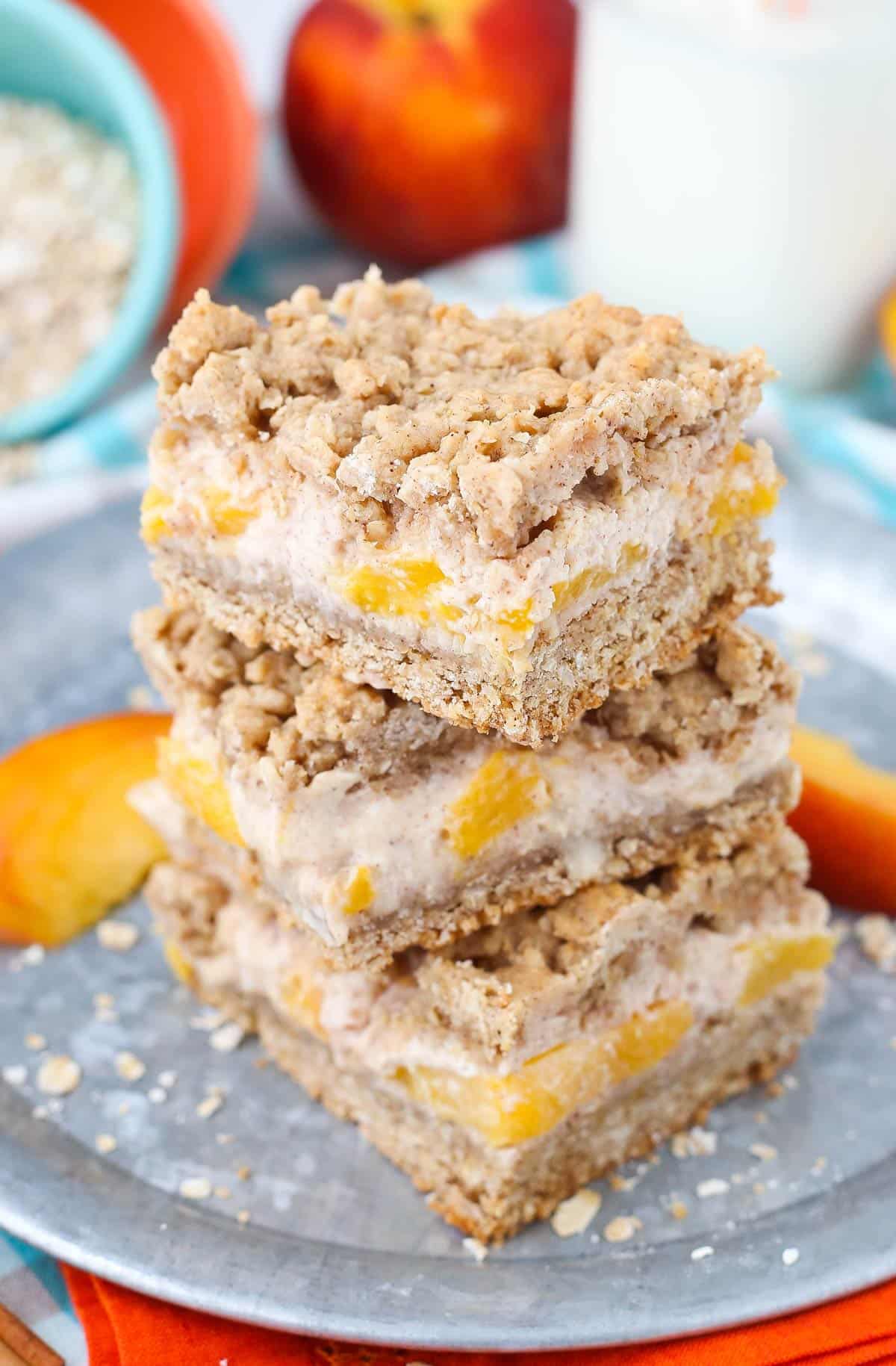 Three peach cinnamon oatmeal cheesecake bars stacked one on top of the other.