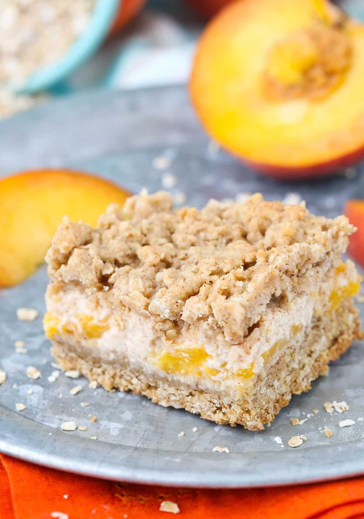 Close up of a peach cinnamon oatmeal cheesecake bar on a silver tray.