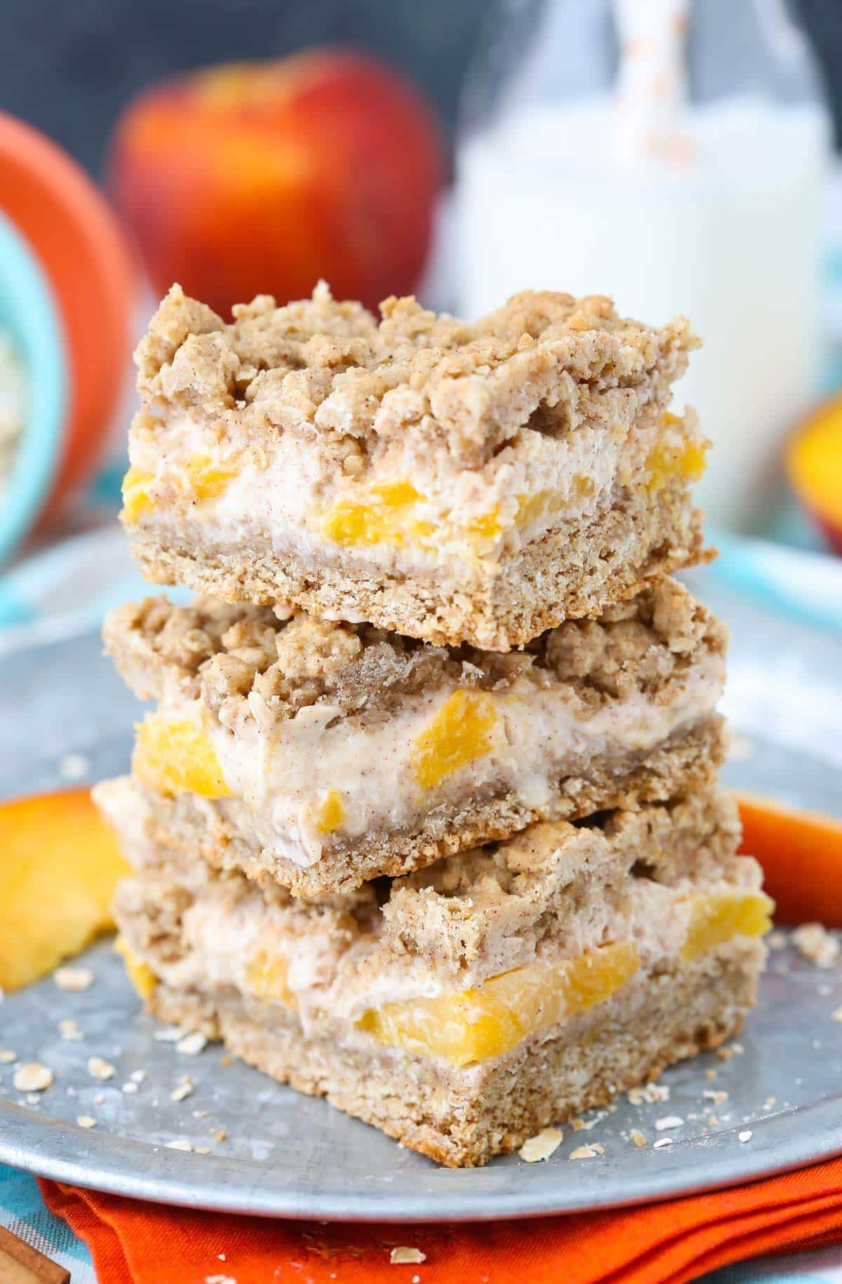 Three peach cinnamon oatmeal cheesecake bars stacked one on top of the other.