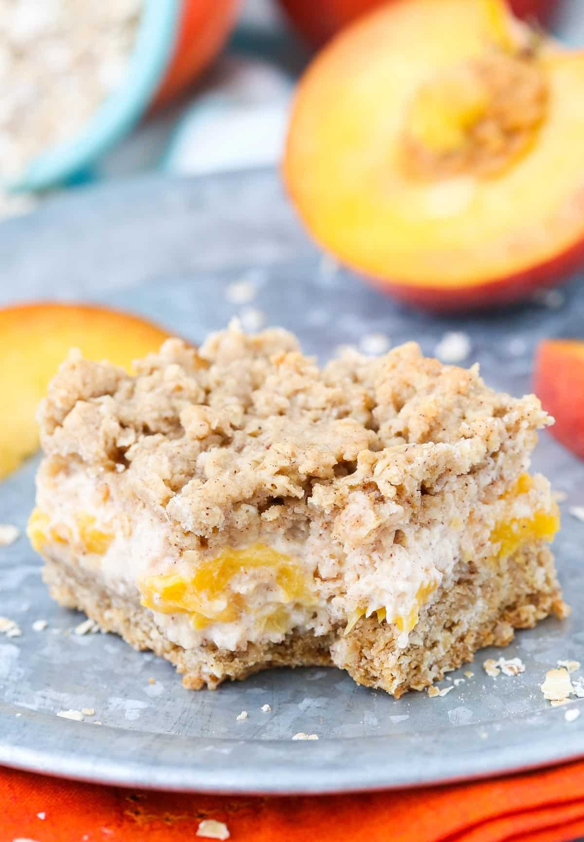 Close up of a peach cinnamon oatmeal cheesecake bar with a bite taken out of it.