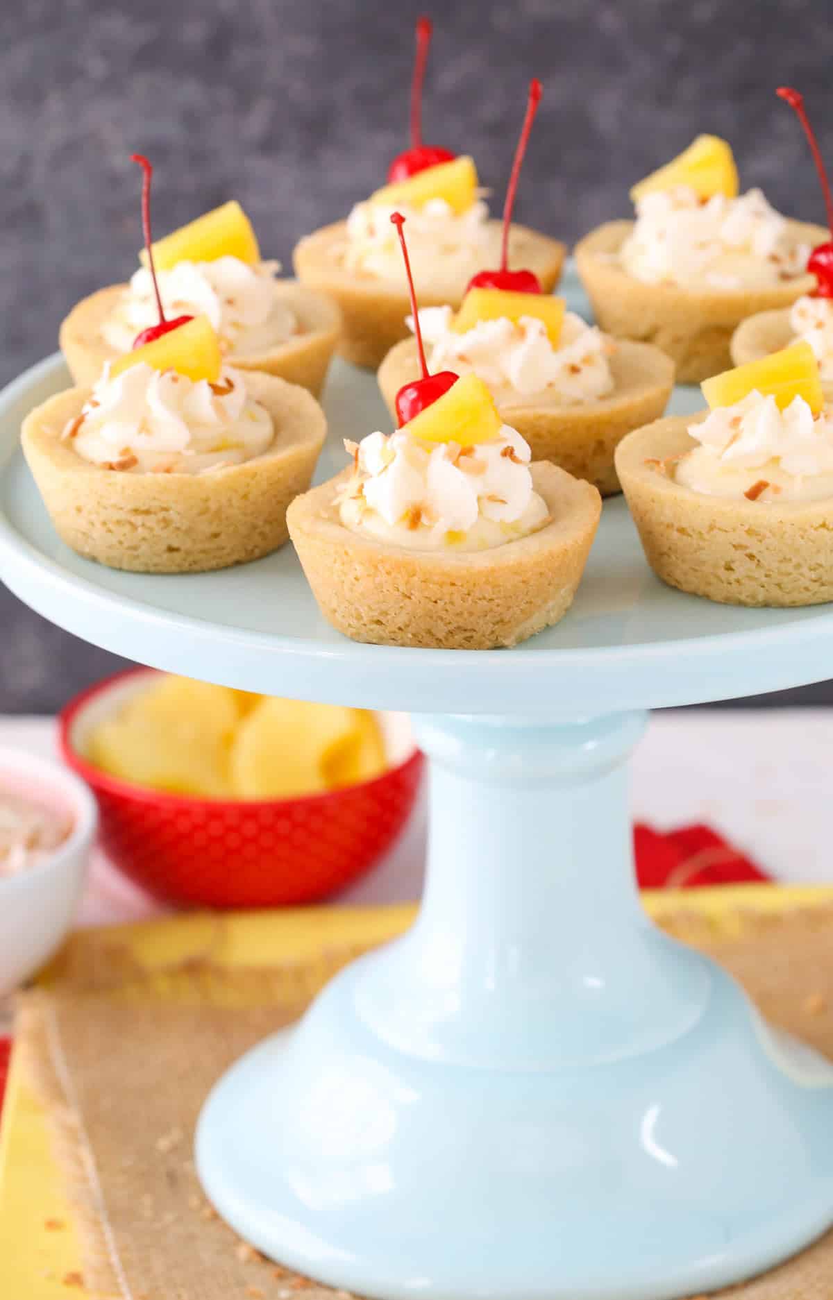 A light blue cake stand covered with pina colada cookie cups.
