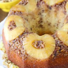 Close up of the top of a pineapple walnut upside down cake on a white cake plate.