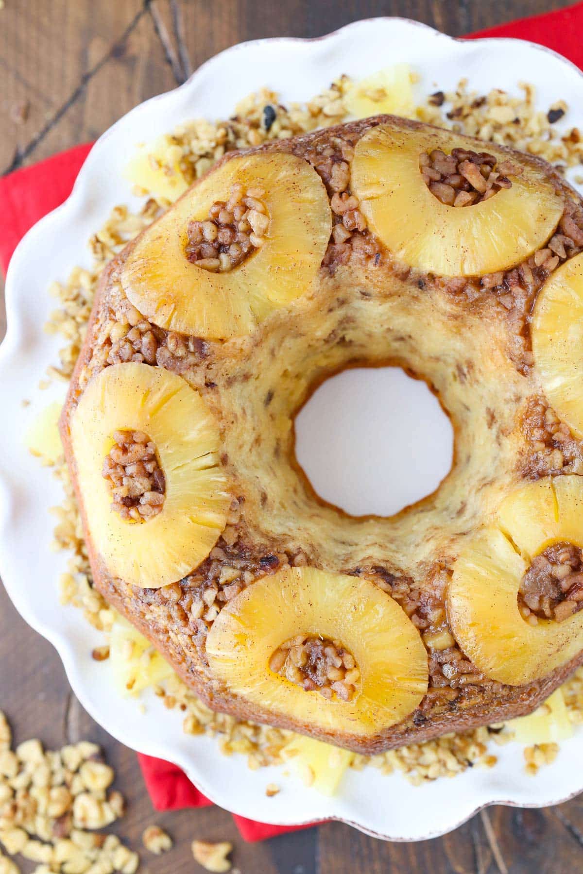Close up of a pineapple walnut upside down cake on a white cake plate.