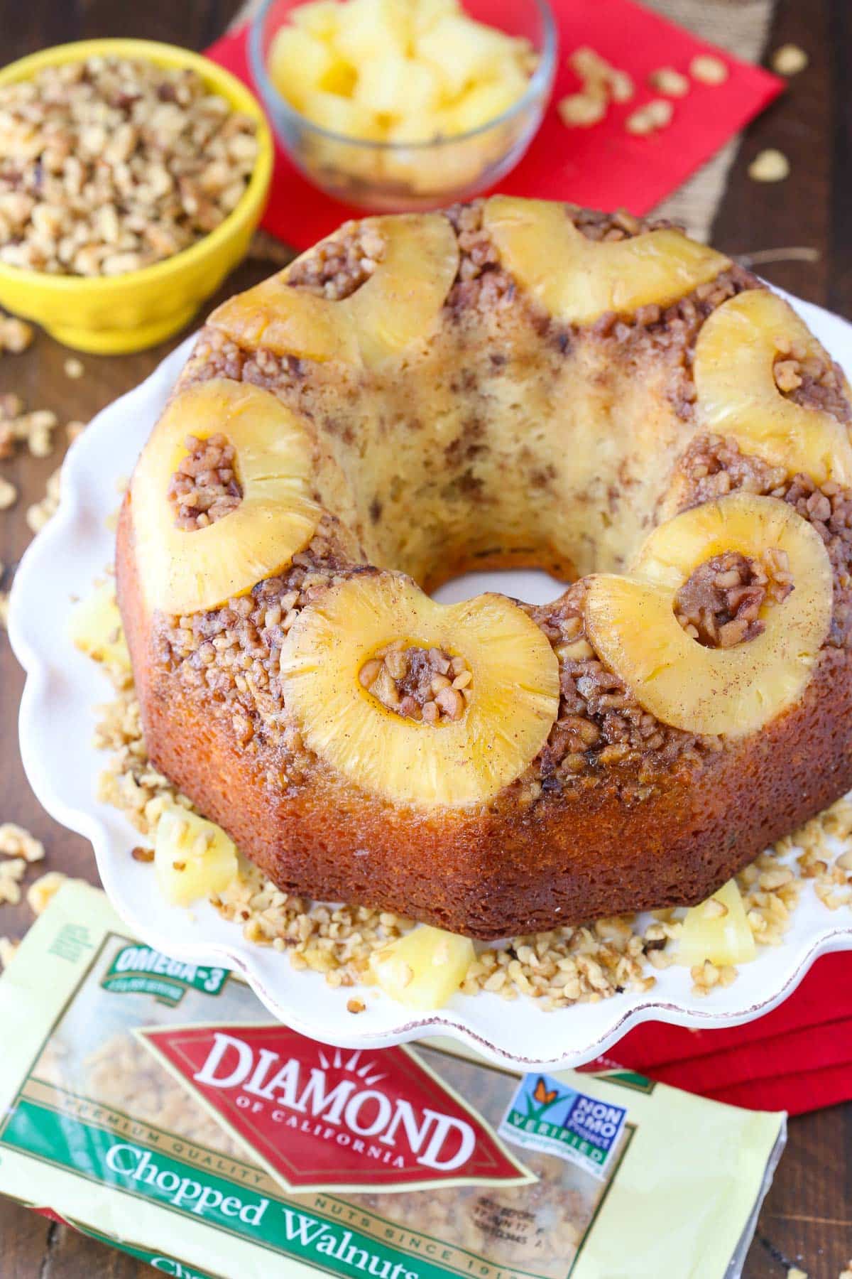 A pineapple walnut upside down cake on a white ruffled cake plate.