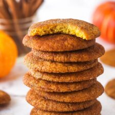 A stack of pumpkin snickerdoodle cookies. The top cookie has a bite taken out of it.