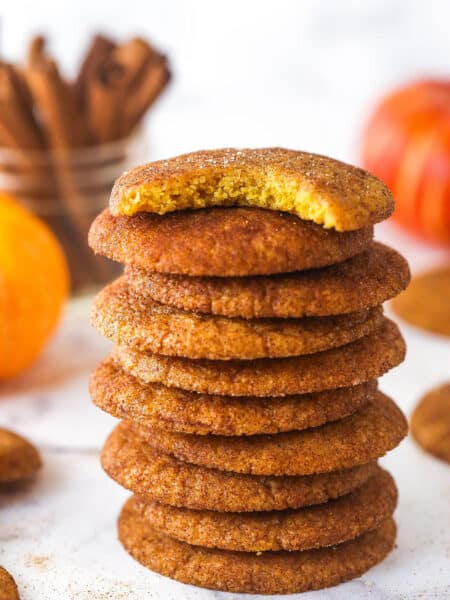A stack of pumpkin snickerdoodle cookies. The top cookie has a bite taken out of it.
