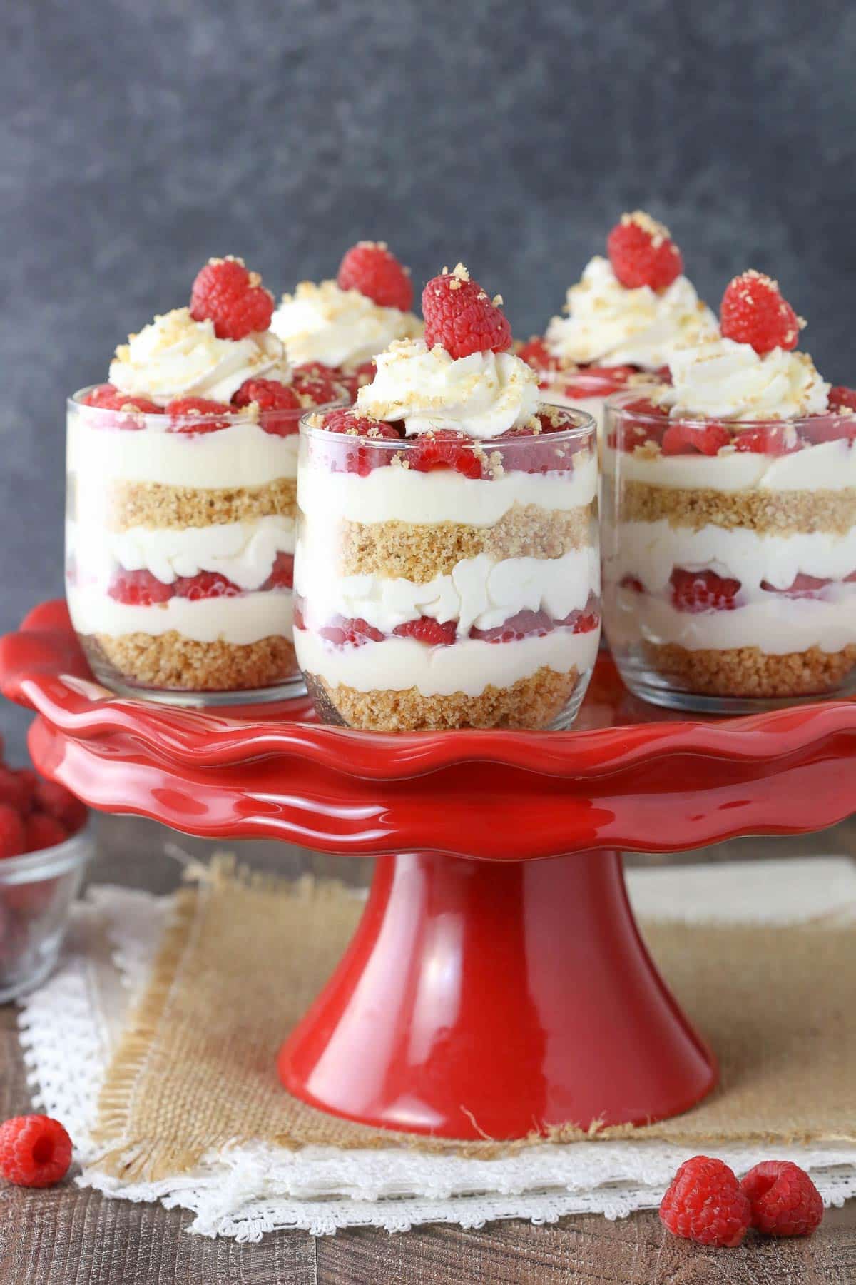 Five raspberry amaretto cheesecake trifles on a red cake stand.