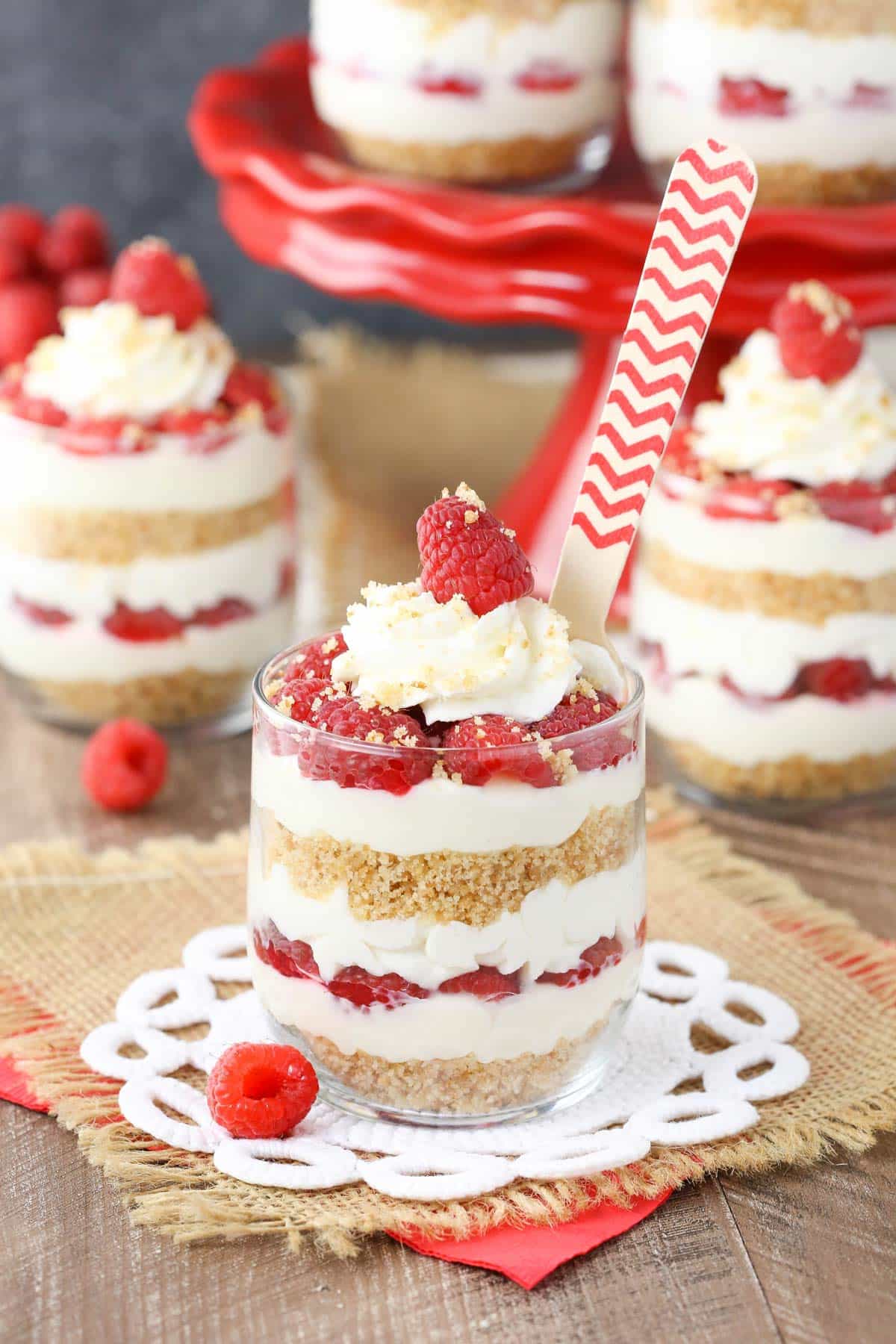 Close up of a raspberry amaretto cheesecake trifle with more trifles in the background.
