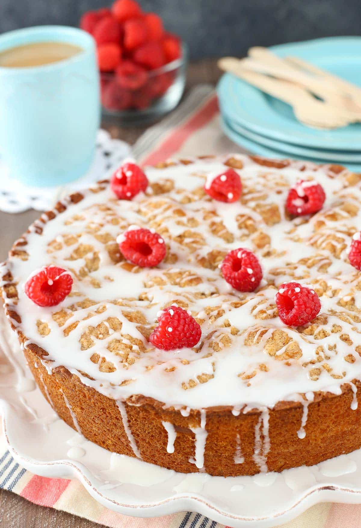 Close up of a raspberry cream cheese coffee cake on a white ruffled cake plate.