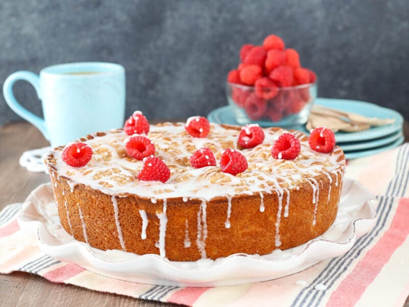 A raspberry cream cheese coffee cake on a white ruffled cake plate.