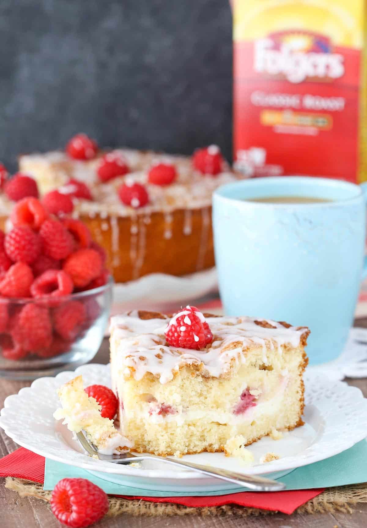 A slice of raspberry cream cheese coffee cake with a bite removed on a small white plate.
