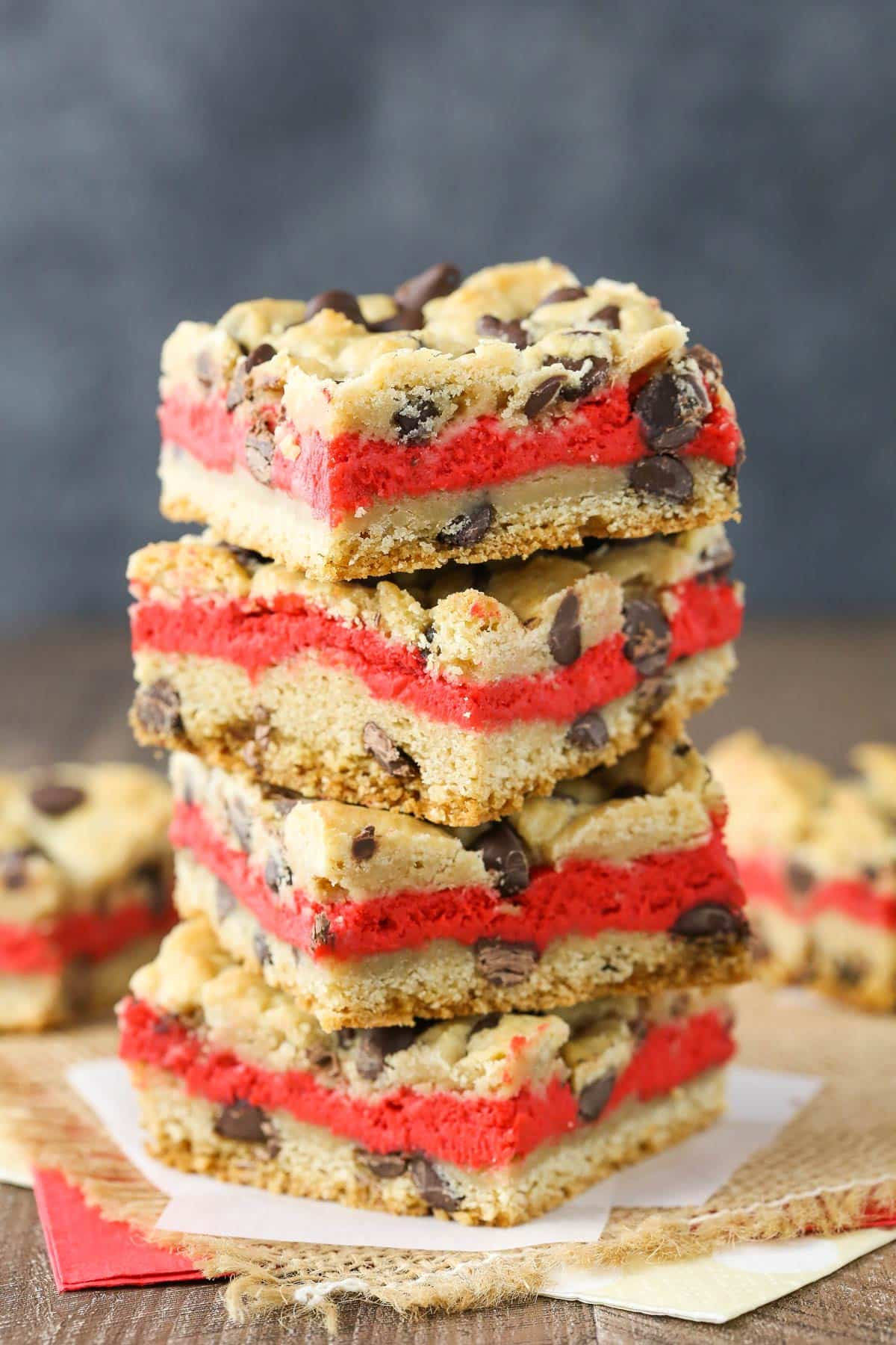 Close up of a stack of four red velvet cheesecake chocolate chip cookie bars.