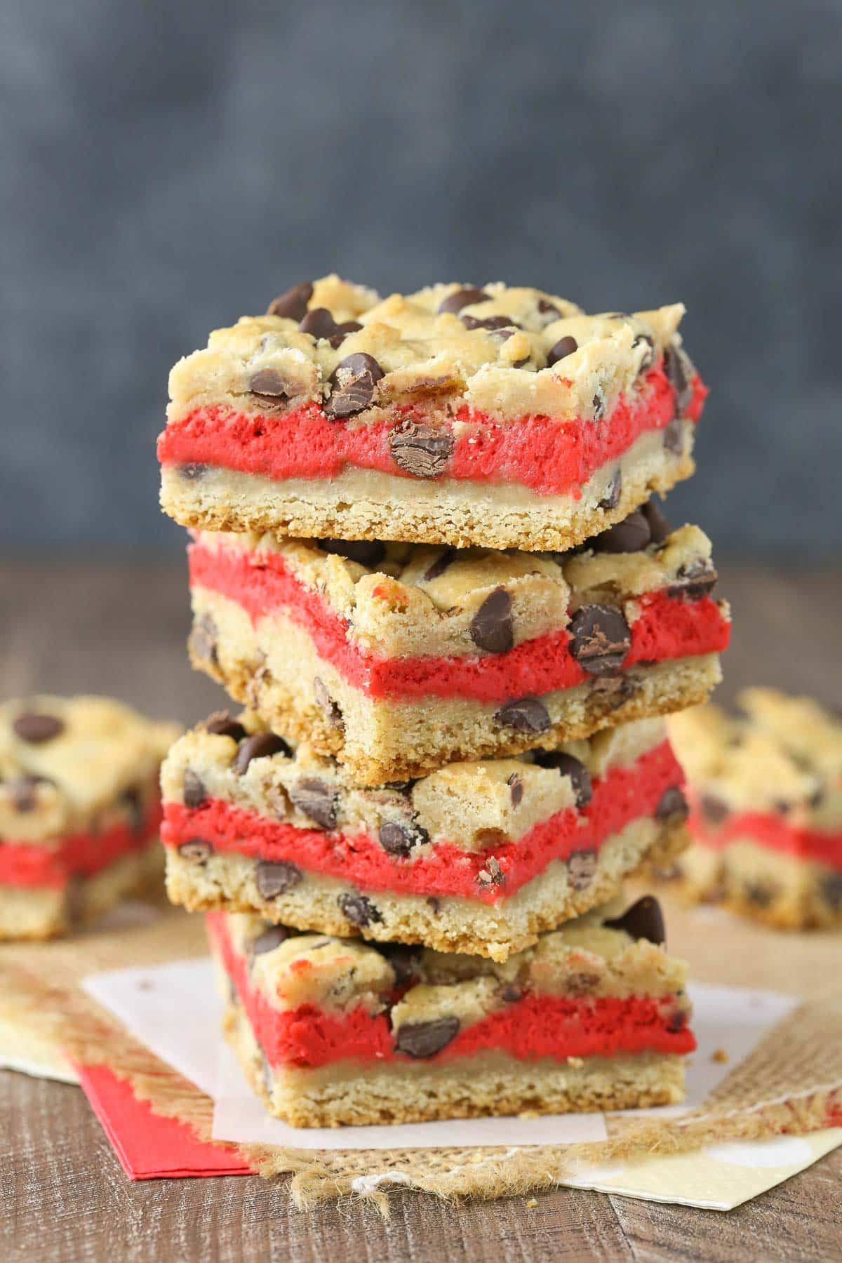 Close up of a stack of four red velvet cheesecake chocolate chip cookie bars.