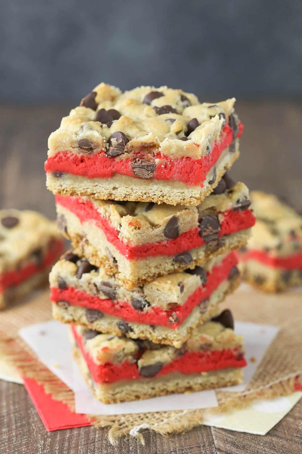 Side view of a stack of 4 red velvet cheesecake chocolate chip cookie bars.