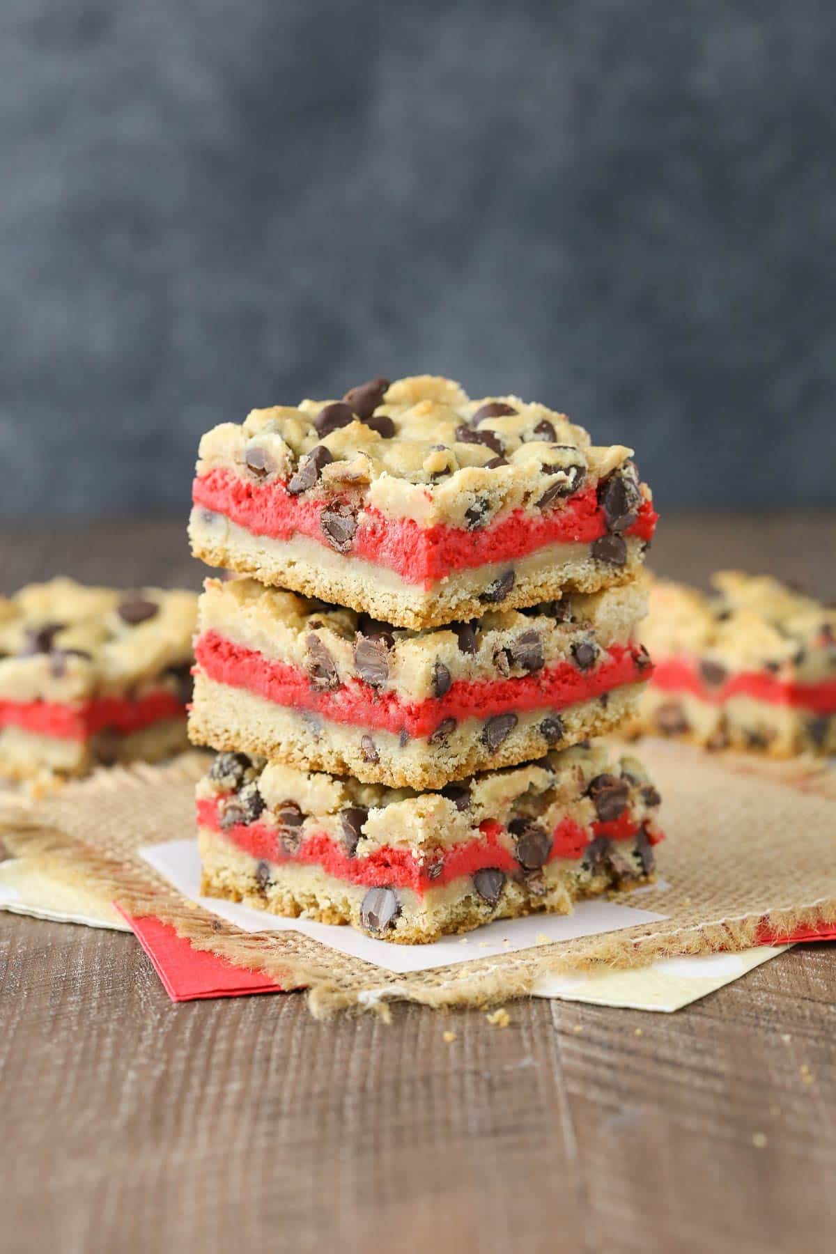 A stack of three red velvet cheesecake chocolate chip cookie bars.