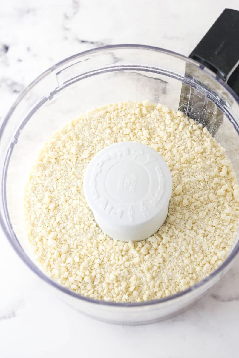 Butter, flour, and salt pulsed together in a food processor to create a sand-like consistency for pie dough.