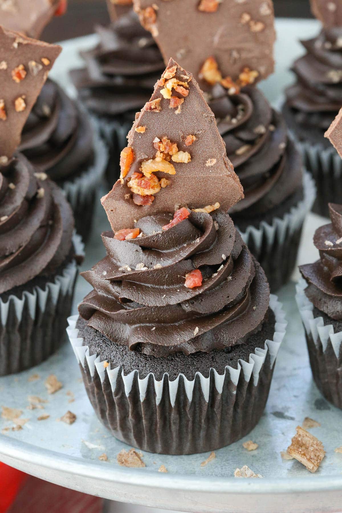 Close up of a plate of smokey bourbon chocolate cupcakes with bacon bark.