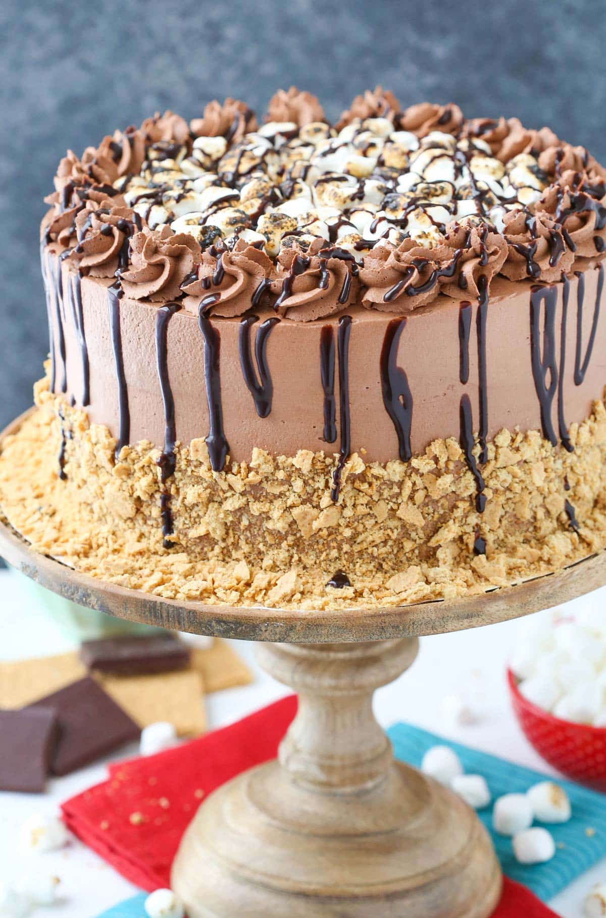 A s'mores ice cream cake on a wooden cake stand.