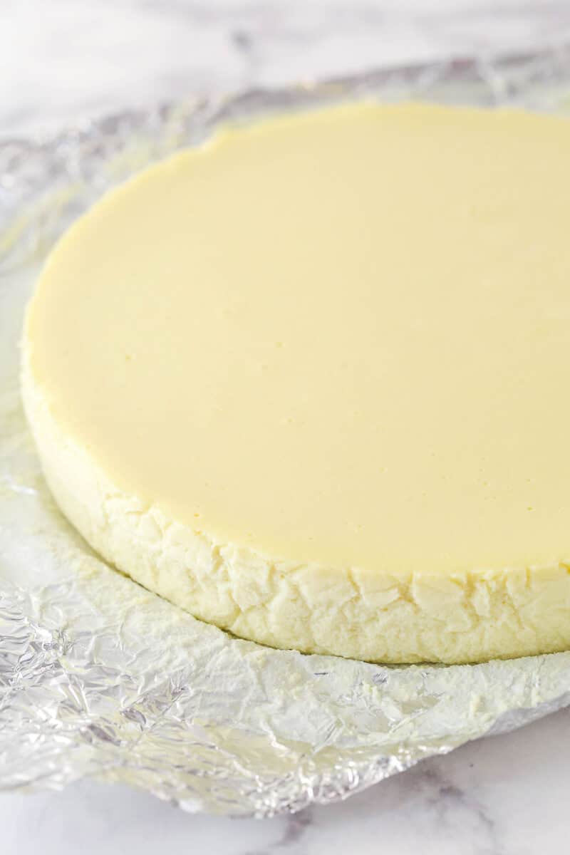 A layer of cheesecake on a piece of aluminum foil.