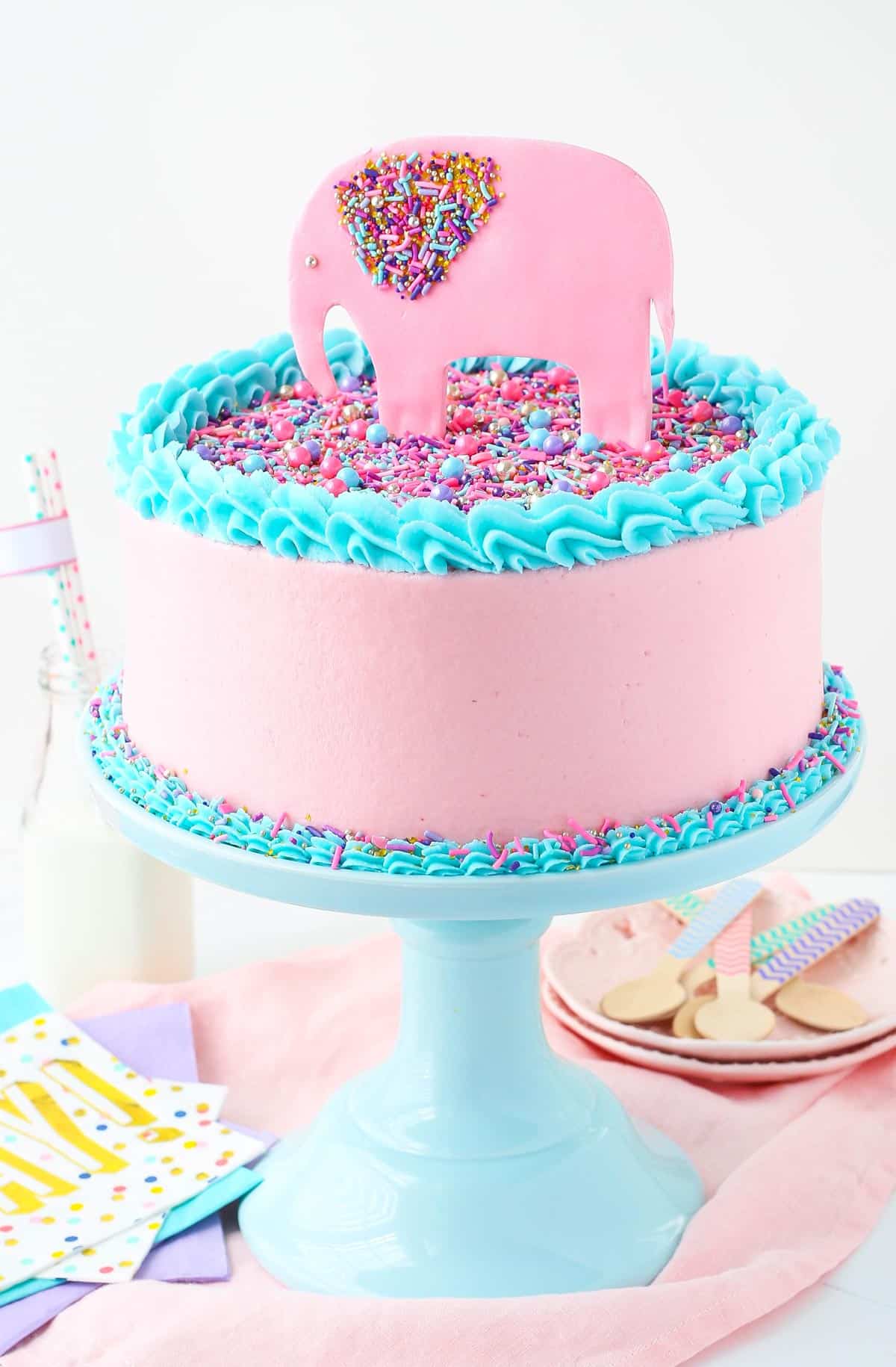 A strawberry layer cake with a pink fondant elephant decoration on top.
