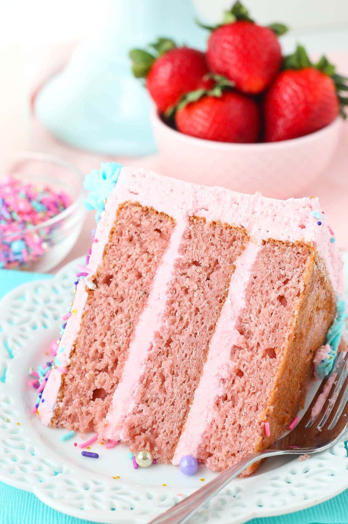 Close up of a piece of strawberry layer cake on a white plate.