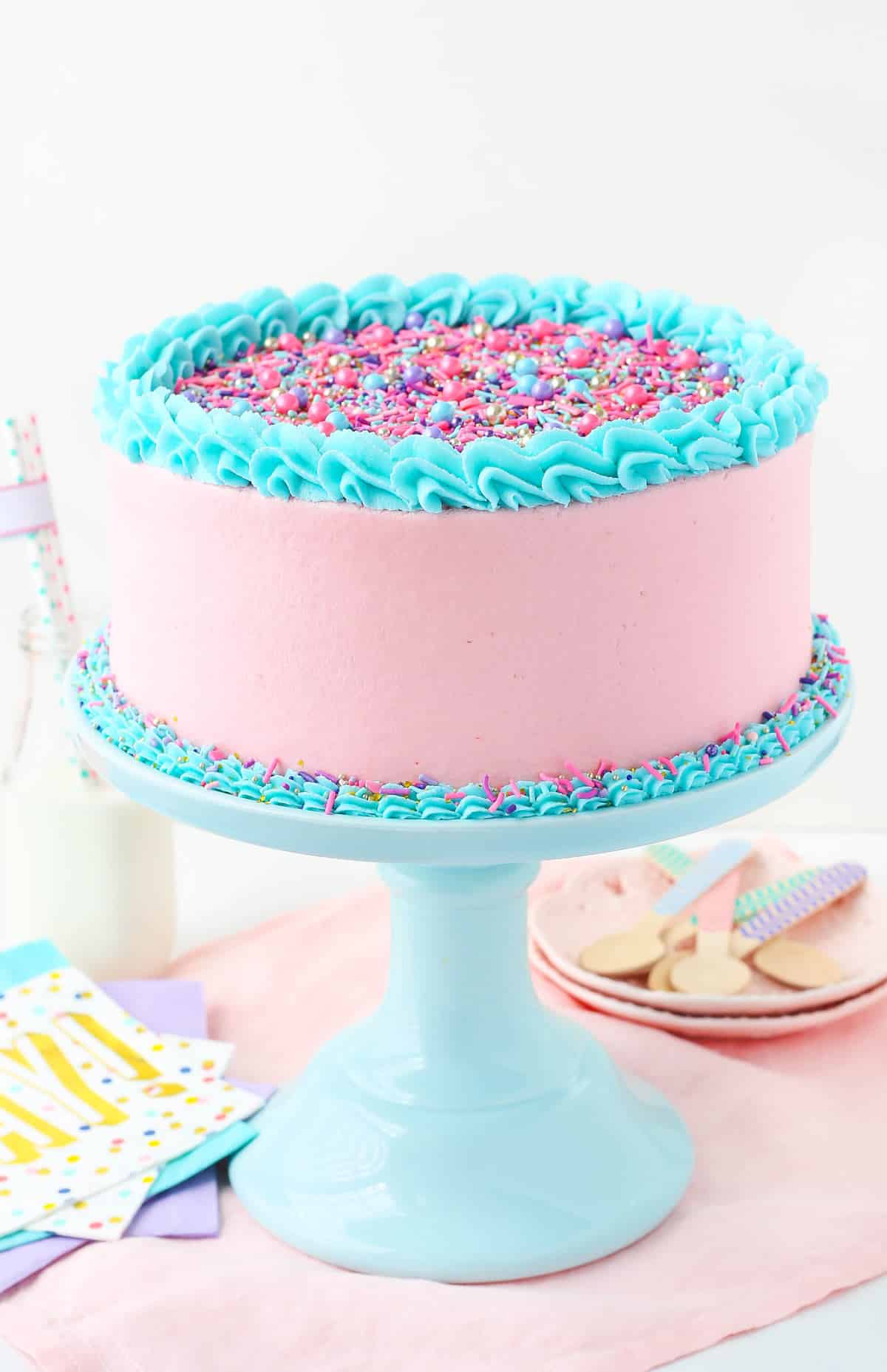 A strawberry layer cake on a light teal cake stand.