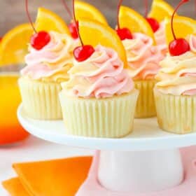 A white cake stand covered in tequila sunrise cupcakes.