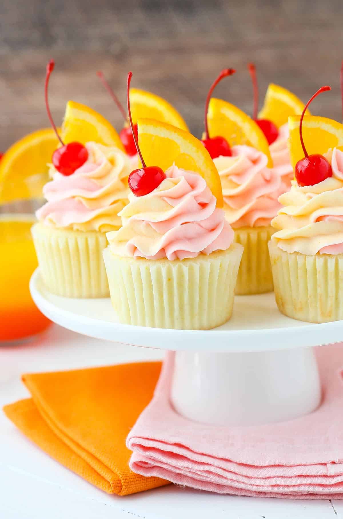 A white cake stand covered in tequila sunrise cupcakes.