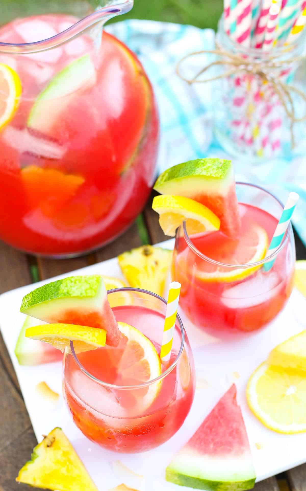 Top view of two tropical watermelon lemonade cocktails with a pitcher in the background.