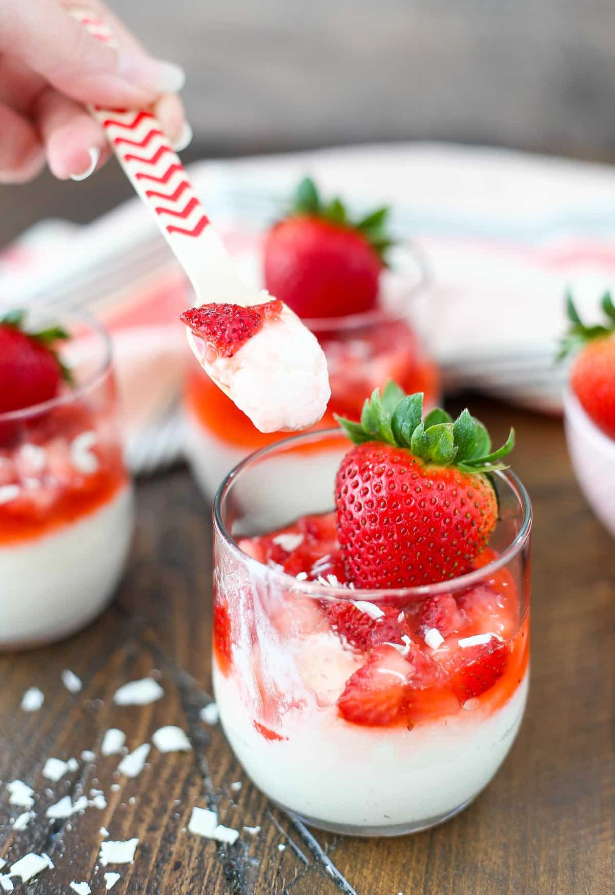 A strawberry white chocolate mousse cup with a spoon lifting up a bite.