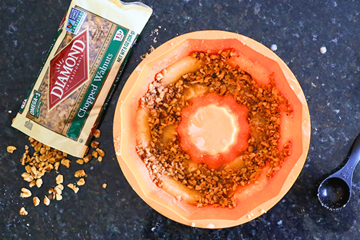 An orange bundt pan will with the toppings for a pineapple walnut upside down cake.