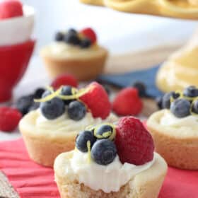 Close up of a berry lemon cheesecake cookie cup with a bite taken out of it.