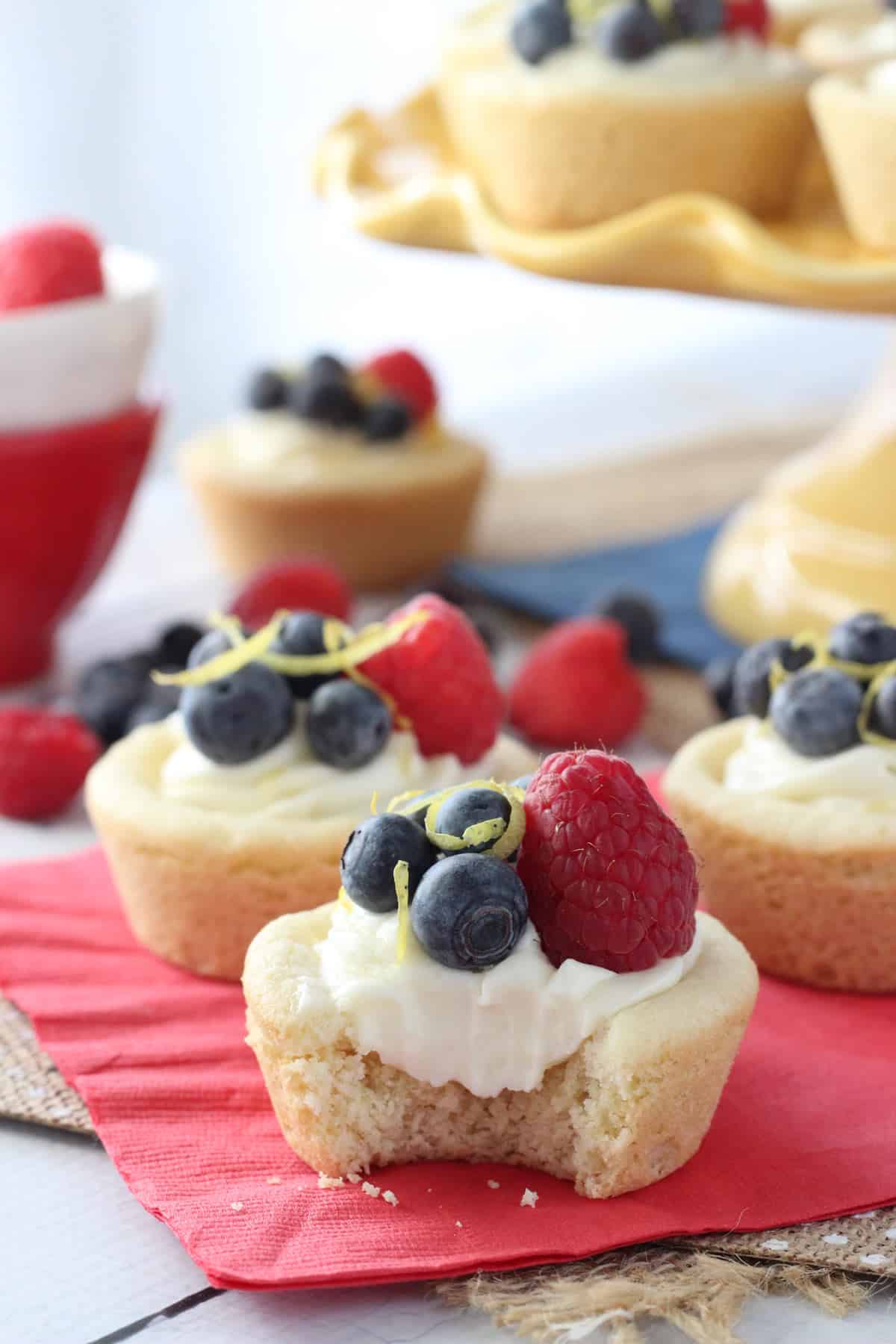 Close up of a berry lemon cheesecake cookie cup with a bite taken out of it.