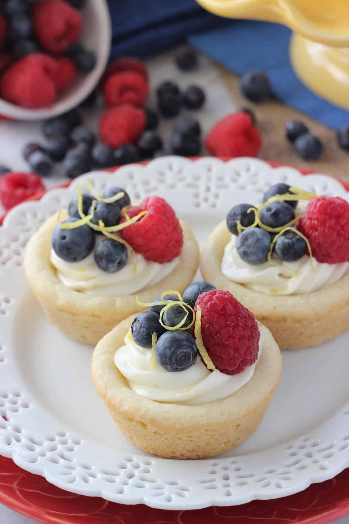 Three berry lemon cheesecake cookie cups on a small white plate.